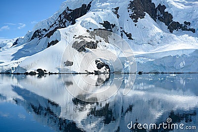 Typical antarctic landscape with high mountain chain reflecting in ocean. Glacier reaching to the sea, Antarctica. Stock Photo