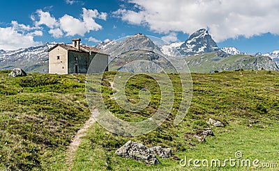 Mountain church in an idyllic mountain landscape in the summertime in the Alps with snow-capped peaks in the background Stock Photo