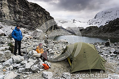 Male and female mountain climber at a high camp in the Andes in Peru with a tent and lake in the foreground Stock Photo