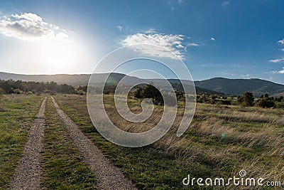 Mountain forest landscape under evening sky with clouds in sunlight road in forest Stock Photo