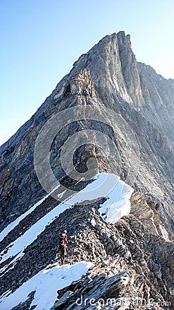 Mountain guide leading two male clients to a rocky ridge and onwards to a high alpine summit Editorial Stock Photo