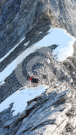 Mountain guide leading two male clients to a rocky ridge and onwards to a high alpine summit Editorial Stock Photo