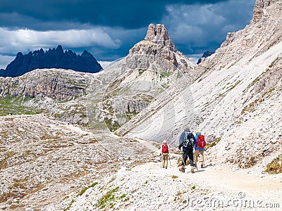 Mountain hikers with trekking poles walks on the rocky path in the mountains. Nordic walking theme Editorial Stock Photo