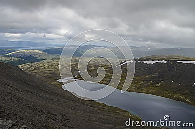 Mountain lake in valley with mosses and rocks covered with lichens. Cloudy sky before storm. Khibiny mountains above the Arctic Stock Photo