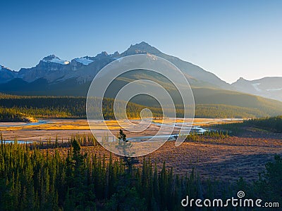 Mountain landscape at dawn. Sunbeams in a valley. Rivers and forest in a mountain valley at dawn. Stock Photo