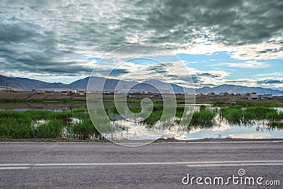 Mountain landscape in the early morning. The sky is reflected in the lake. In the distance there is a village. Stock Photo