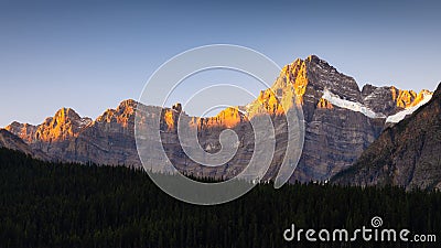 Mountain landscape at sunrise. Sunbeams in a valley. High rocks and forest in a mountain valley at dawn. Natural landscape with br Stock Photo