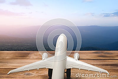 Mountain landscape with a view of the forest and white model of passenger plane on old wooden background. Stock Photo
