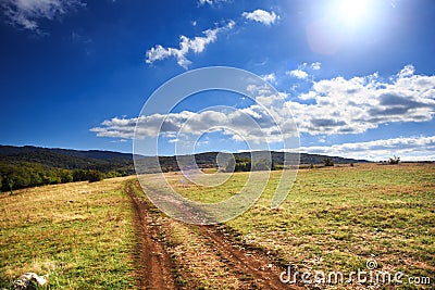 Mountain path leads through plain with beautiful scenic mountain Stock Photo