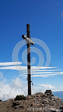 Mountain peak cross with cloudy blue sky in the background Stock Photo