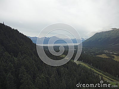 Mountain Range with Forests and Stream. Lush temperate rainforest in alaska with clouds and sun Stock Photo