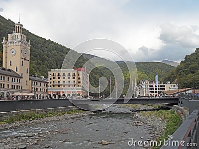The mountain resort Rosa Khutor on the embankment of the river, the clock tower, bridge, hotels Editorial Stock Photo