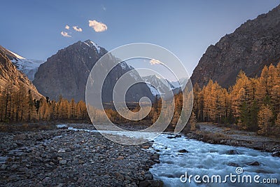 Mountain river on the background of autumn forest, snow capped mountains and blue sky Stock Photo