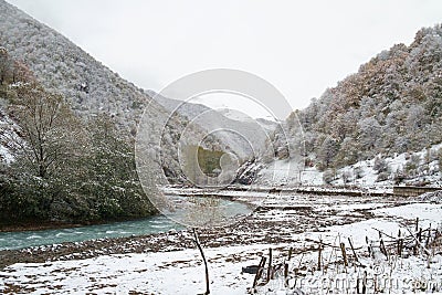 Mountain river flows in a snowy valley Stock Photo