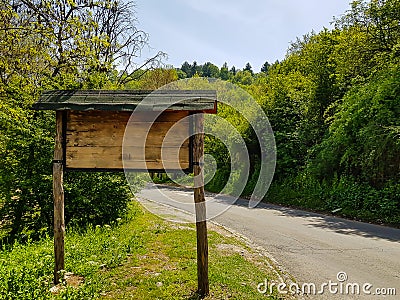 Mountain road sign, made out of wood next to road Stock Photo