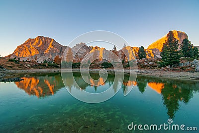 Mountain rocks and autumn trees reflected in water of Limides Lake at sunset, Dolomite Alps, Italy Stock Photo