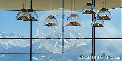 Mountain-shaped lamps hang inside a restaurant opposite a snow-capped mountains window in Austrian Alps.Selective focus on lamps Stock Photo