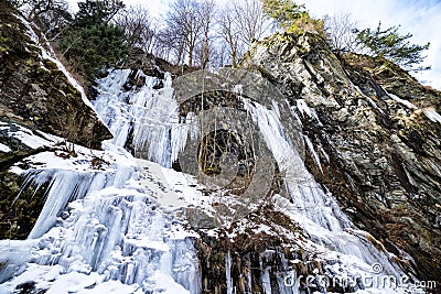 Icicle waterfalls sloping down a mountain side during a cold winter day Stock Photo