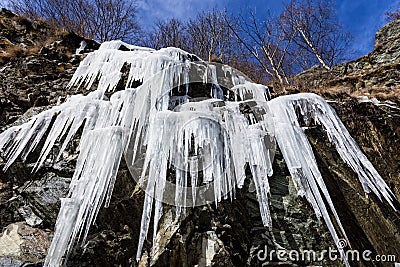 Amazing icicles hanging from a rock formation in the mountains during cold winter Stock Photo