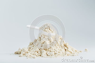 A mountain of soy protein isolate in powder with a measuring spoon on a white background. Stock Photo