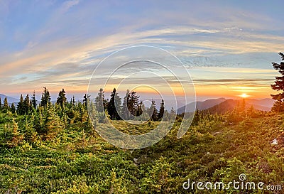 Mountain Sunset: A Golden Orange Glow Silhouettes the Distant Peaks and Wooded Landscape Stock Photo