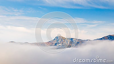 A mountain surrounded by fog in the autumn season Stock Photo