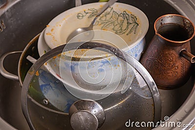 A mountain of unwashed utensils in a kitchen sink. Desolation and mess Stock Photo
