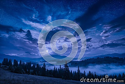 Mountain valley with stars in a cloudy night sky Stock Photo