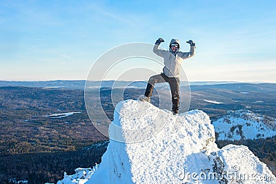 The mountaineer climbed the mountain top covered with ice and snow, man hiker standing at the peak of rock and Stock Photo