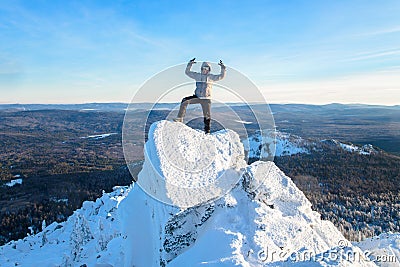 The mountaineer climbed the mountain top, man hiker standing at the peak of rock and celebrates the success. Stock Photo