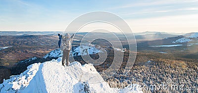 The mountaineer climbed the mountain top, man hiker standing at the peak of rock and celebrates the success with raised Stock Photo