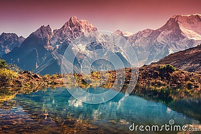 Mountains with snow covered peaks, red sky reflected in lake Stock Photo