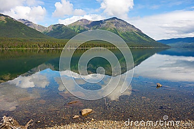 Mountains and trees reflected in a calm lake along the cassiar highway Stock Photo
