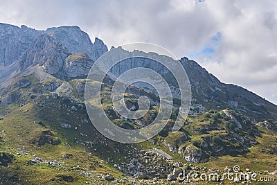 Mountainside with green ledges, and above it an impregnable rocky peak Stock Photo
