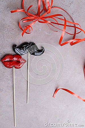 Moustache and a red mouth on wooden sticks against a split stone background copy space for your text as the male and female concep Stock Photo