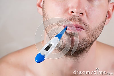 Mouth of an unshaven man holding an electronic thermometer in his mouth Stock Photo