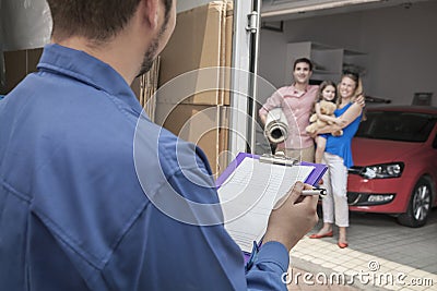 Mover holding clipboard and invoice, family in the background Stock Photo