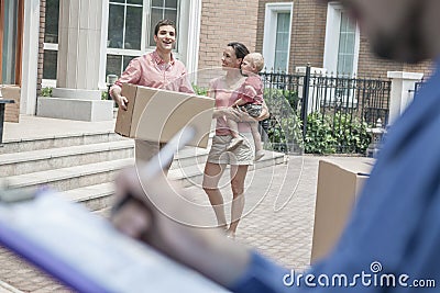 Mover holding clipboard and invoice, family in the background Stock Photo