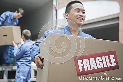 Movers unloading a moving van and carrying a fragile box Stock Photo