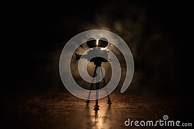 Movie concept. Miniature movie set on dark toned background with fog and empty space. Silhouette of vintage camera on tripod Stock Photo