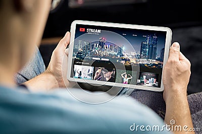 Movie and series stream VOD service in tablet. Watching on demand tv show or film online. Man choosing video entertainment. Stock Photo