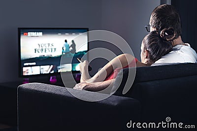 Movie stream service on smart tv. Couple watching series online. Woman choosing film or new season with remote control. Stock Photo