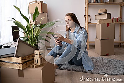 Moving day. Home move out of apartment moving boxes woman using online movers services on mobile phone app, easy pick-up Stock Photo