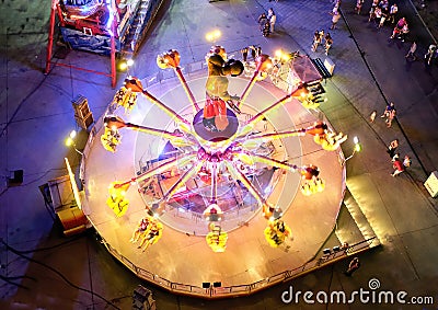 Moving fairground attraction seen from above with people around it Editorial Stock Photo