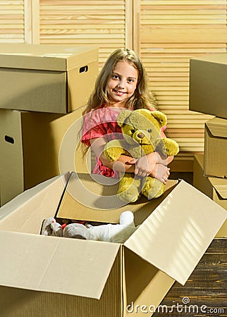 Moving routine. Only true friend. Girl child play with toy near boxes. Packaging things. Move out concept. Stressful Stock Photo