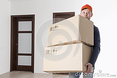 Moving service relocation. Mover holding two cardboard box in apartment`s room. loader is transporting things to apartment. Stock Photo