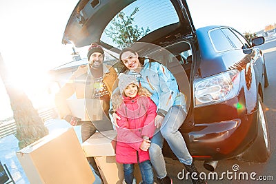 Moving to new apartment. Family together outdoors standing sitting at car with boxes smiling happy Stock Photo