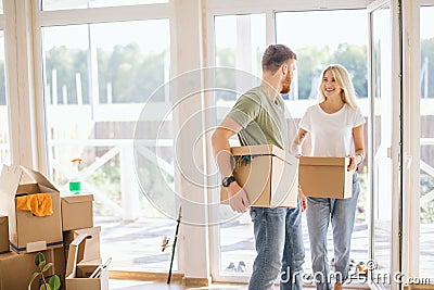 Happy Couple Carrying Cardboard Boxes Into New Home On Moving Day Stock Photo