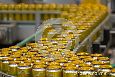 Moving yellow aluminium beer cans on conveyor belt at brewery plant Stock Photo