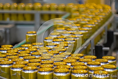 Moving yellow aluminium beer cans on conveyor belt at brewery plant Stock Photo